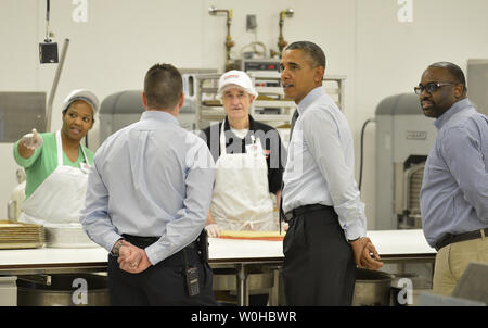 Il Presidente Usa Barack Obama (C) Visite con la Costco bakers (dietro la tabella) come egli è scortato da Costco dipendenti Ray Queved (L) e Rickey Banner come egli tours il negozio prima di fornire osservazioni in un negozio di rally, come egli prende il suo stato dell unione indirizzo su una escursione di due giorni al di fuori di Washington, in Lanham, Maryland, 29 gennaio 2014. Obama sta spingendo il Congresso a sollevare la Federal salario minimo come parte del suo piano economico. UPI/Mike Theiler Foto Stock