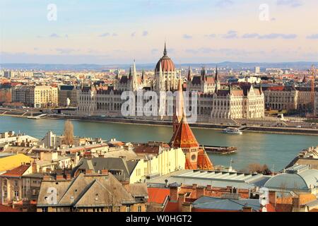 Vista sul lato Buda di Budapest e del Danubio, ungherese della Casa del Parlamento che si siede sul lato Pest del Danubio banche. Foto Stock