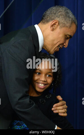 Stati Uniti Il presidente Barack Obama abbracci terzo-grader Alajah Lane, 9, dell'Occidente istruzione Campus in Washington, DC, dopo che lei lo ha presentato alla Casa Bianca il vertice sulla formazione iniziale nel sud Corte Auditorium del Eisenhower Executive Office edificio adiacente alla Casa Bianca di Washington, DC su dicembre 10,2014. Il vertice comporta importanti business leader, filantropi, i funzionari eletti e i membri del pubblico impegnato per l'espansione di alta qualità della formazione iniziale per i bambini. UPI/Pat Benic Foto Stock