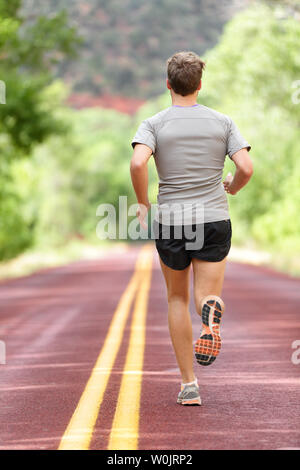 Uomo che corre runner che lavora fuori per il fitness. Atleta maschio su jogging run sport di indossare scarpe da corsa e pantaloncini che lavora fuori per la maratona. Corpo pieno lunghezza vista che mostra torna a fuggire. Foto Stock