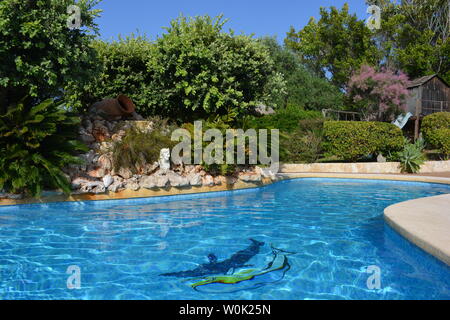 Piscina con un rockery in un giardino mediterraneo in estate. Foto Stock