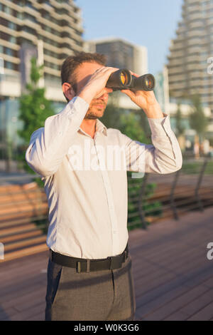 Il giovane imprenditore con un binocolo a spiare i concorrenti concetto creativo. Foto Stock