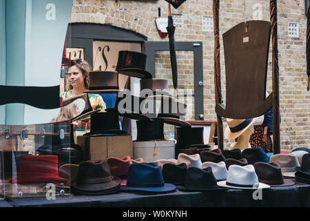 London, Regno Unito - 22 giugno 2019:Le persone che ricercano cappelli alla pressione di stallo all'interno di Spitalfields Market, uno dei più raffinati superstite mercato vittoriano sale in London wi Foto Stock