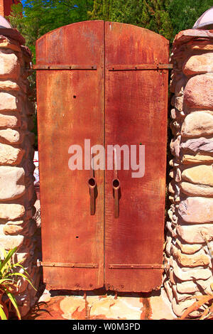 Due metallo arrugginito porte con pick-ax capi per maniglie che conduce al cortile ristorante birreria su Ave nel centro cittadino di Bisbee, AZ Foto Stock