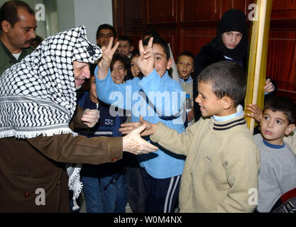 Il leader palestinese Yasser Arafat Sorride e scuote le mani con i bambini nel corso di un incontro con i portatori di handicap palestinese unione della delegazione presso il suo ufficio a Ramallah Dicembre 4, 2003. (UPI foto/Omar Rashidi/Autorità palestinese) Foto Stock