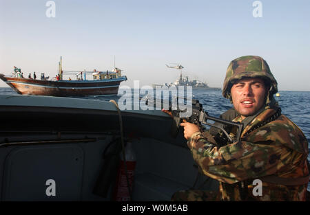 Un italiano di marina da italiano classe Maestrale fregata, la sua Scirocco (F 573) consente di impostare la sicurezza per il resto del suo team di sicurezza a bordo di un cargo locale dhow per condurre una ricerca del peschereccio nel Golfo di Oman il 3 maggio 2004. (UPI foto/Bart Bauer/Navy US) Foto Stock