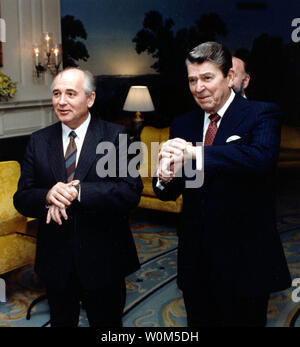 Il Presidente Ronald Reagan e il leader sovietico Mikhail Gorbaciov sono visto qui controllare i loro orologi in attesa che le loro mogli di emergere dal loro parlare alla Casa Bianca il 9 dicembre 1987. (UPI/File) Foto Stock