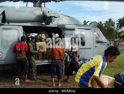 Aviation Electronics tecnico di terza classe Jon Charles distribuisce le scatole di bottiglia di acqua da un MH-60S Knighthawk elicottero, assegnato al 'Gunbearers' di elicottero di lottare contro lo squadrone di supporto per uno (HC-11), in Kuede Teunom, Indonesia, a gennaio 13, 2005. (UPI foto/Ryan Valverde/MARINA) Foto Stock