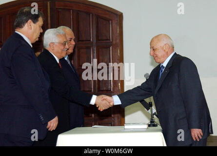 Autorità Palestinese Presidente Mahmoud Abbas scuote le mani con il Primo ministro palestinese Ahmed Qureia (R) durante il giuramento del nuovo armadio in Cisgiordania città di Ramallah, Feb 24, 2005. Cerca su altoparlante sono Raui Fattouh (L) e Tayeb ufficiale Abd al Rahim. Il parlamento palestinese ha approvato un 24-stati armadio dominato dai professionisti incaricati. (UPI foto/Omar Rashidi/Autorità palestinese) Foto Stock