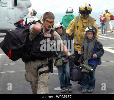 Stati Uniti I marinai della marina assistere due giovani cittadini americani come essi arrivano sul ponte di volo della USS Trenton (LPD 14) come la nave opera al largo delle coste del Libano il 21 luglio 2006. Su richiesta degli Stati Uniti Ambasciatore in Libano e presso la direzione del Segretario della Difesa degli Stati Uniti centrali di comando e gli elementi della Task Force 59 stanno aiutando con la partenza di cittadini degli Stati Uniti dal Libano. Il Trenton è un trasporto anfibio che è usato per trasportare e terreni di Marines, le loro attrezzature andsupplies avviato dal cuscino d'aria o convenzionali di landing craft, veicoli anfibi, helicopte Foto Stock