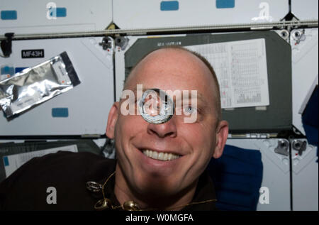 L'astronauta della NASA Clayton Anderson, STS-131 lo specialista di missione, orologi una bolla di acqua di flottare liberamente tra lui e la fotocamera, che mostra la sua immagine rifratta, sul middeck della navetta spaziale Discovery mentre è inserito con la Stazione Spaziale Internazionale il 12 aprile 2010. UPI/NASA Foto Stock