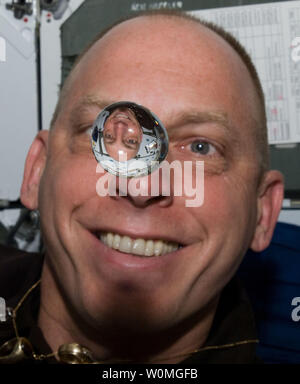 L'astronauta della NASA Clayton Anderson, STS-131 lo specialista di missione, orologi una bolla di acqua di flottare liberamente tra lui e la fotocamera, che mostra la sua immagine rifratta, sul middeck della navetta spaziale Discovery mentre è inserito con la Stazione Spaziale Internazionale il 12 aprile 2010. UPI/NASA Foto Stock