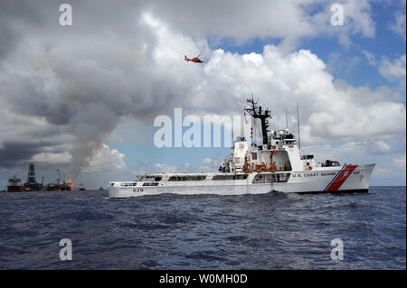 Un Coast Guard HH-65 Delfino elicottero vola in testa come il guardacoste risoluta vapori vicino Deepwater Horizon spill sito su luglio 4, 2010 nel Golfo del Messico. UPI/Matteo Belson/STATI UNITI Coast Guard Foto Stock