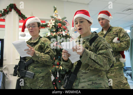 Stati Uniti Esercito 1Lt. Cecelia Anderson (sinistra) di Natchitoches, La., U.S. Il personale dell'esercito Sgt. Jackie Malloy (centro) del Centro di stato, Iowa, E DEGLI STATI UNITI Army Sgt. Jarrod Hogan (retro) di Cedar Rapids, Iowa, tutti con 334 Vigili del battaglione di supporto, Task Force Archer, cantare i canti natalizi per il personale e i pazienti al personale Sgt. Heathe N. Craig Teatro comune ospedale, Bagram Airfield, Afghanistan, Dicembre 24, 2010. UPI/Kristina L. Gupton/DOD Foto Stock