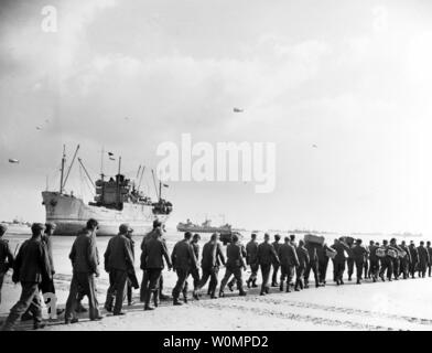 Prigionieri di guerra tedeschi sono hanno marciato verso il basso un invasione della Normandia spiaggia per essere trasferiti alle navi offshore il 12 giugno 1944, dopo l'invasione alleata di tedesco-Francia occupata. Nota il cargo essiccazione a bassa marea. Foto di U.S. Navy/Archivi Nazionali/UPI Foto Stock