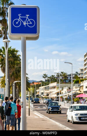 CANNES, Francia - Aprile 2019: Segno al di sopra di una pista ciclabile accanto ad una strada sul lungomare di Cannes Foto Stock