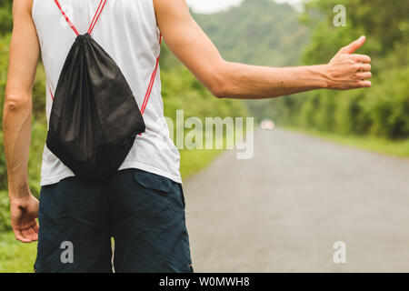 Giovani turisti sulla strada hitckhiking donna voti sulla strada. Bella ragazza sulla strada. Un uomo si arresta la macchina Foto Stock