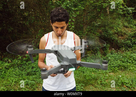 Giovane uomo imparare a volare un drone con in corrispondenza del campo verde Foto Stock