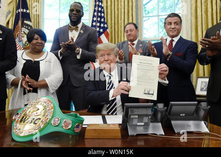 Presidente Donald Trump detiene un esecutivo firmato concessione di clemenza per boxer Jack Johnson all Ufficio Ovale della Casa Bianca il 24 maggio 2018 a Washington, DC. Johnson, il primo afro-americano di heavyweight champion era stato imprigionato per un secolo fa dopo avere un rapporto con una donna bianca.presenti alla manifestazione da L a R : .Linda Haywood, grande grande nipote di Jack Johnson, Deontay Wilder, Keith Frankel, Sylvester Stallone e Lennox Lewis. Foto di Olivier Douliery/UPI Foto Stock