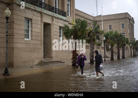 Persone bere birre come essi a piedi attraverso un parzialmente allagate downtown, come il Cape Fear River scorre su South Acqua Santa, dopo l'uragano Florence realizzato approdo, Settembre 14, 2018 in Wilmington, Carolina del Nord. Foto da Al Drago/UPI Foto Stock