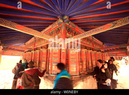 Nomadi tibetani, pellegrini e monaci girare colorato ruote della preghiera che circondano il monastero di Labrang, il più grande monastero tibetano al di fuori di Lhasa, prima per il Tibetano Monlam Festival a Xiahe, provincia di Gansu sull'altopiano tibetano, 2 febbraio 2012. Decine di migliaia di tibetani stanno celebrando il periodo del nuovo anno tibetano rendendo il loro modo di questa città e il suo monastero Labrang, la cui separazione dal Tibetano Regione Autonoma fornisce una misura di protezione dal cinese Han tenta di regolare la loro cultura. UPI/Stephen rasoio Foto Stock