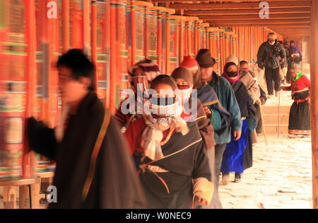 Nomadi tibetani, pellegrini e monaci girare colorato ruote della preghiera che circondano il monastero di Labrang, il più grande monastero tibetano al di fuori di Lhasa, prima per il Tibetano Monlam Festival a Xiahe, provincia di Gansu sull'altopiano tibetano, 2 febbraio 2012. Decine di migliaia di tibetani stanno celebrando il periodo del nuovo anno tibetano rendendo il loro modo di questa città e il suo monastero Labrang, la cui separazione dal Tibetano Regione Autonoma fornisce una misura di protezione dal cinese Han tenta di regolare la loro cultura. UPI/Stephen rasoio Foto Stock