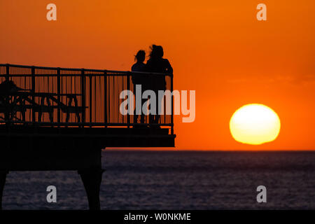 Aberystwyth Wales UK, giovedì 27 giugno 2019 UK Meteo: due donne stand alla fine del molo sul mare, guardando il glorioso tramonto in Aberystwyth su Cardigan Bay costa, West Wales. Il paese è il titolo in un incantesimo di bel tempo con un pennacchio di aria calda fino alla deriva dal continente, accompagnava con essa i giorni più caldi dell'estate finora, con temperature attese per raggiungere l'alta 20's centigradi Photo credit: Keith Morris//Alamy Live News Foto Stock