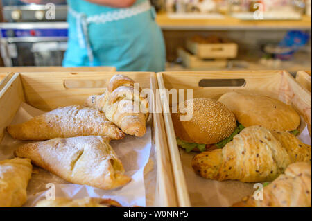 Cornetti e gli hamburger sul contatore in panetteria. I croissant su un basket weave in un panificio. Foto Stock