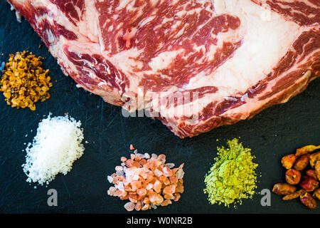 Una fetta di crudo fresco bistecca e colorati di spezie e sale Foto Stock