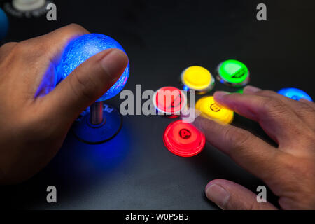Arcade gamer utilizzando un joystick illuminato e combattente layout pulsante con neo geo schema colore. Foto Stock