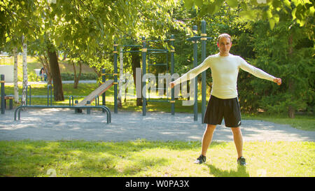 Un uomo atletico eseguire il warm-up prima di esercizi di base - Metà shot Foto Stock