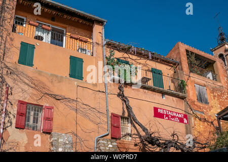 Roussillon, Francia - 22 Gennaio 2019: le case e gli edifici con facciata di colore ocra con pulito cielo blu come sfondo Foto Stock