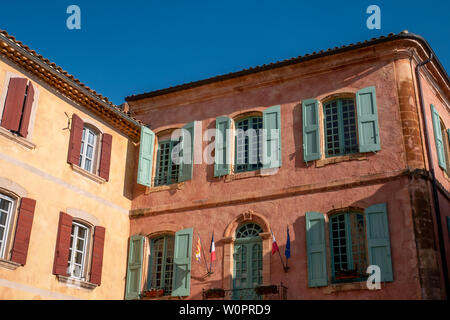 Roussillon, Francia - 22 Gennaio 2019: le case e gli edifici con facciata di colore ocra con pulito cielo blu come sfondo Foto Stock