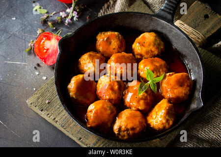 In casa le polpette di carne con spezie e salsa di pomodoro in una padella in pietra scura tabella. Spazio libero per il tuo testo. Foto Stock