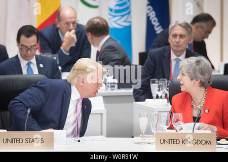 Il presidente statunitense Donald Trump chat con il Primo Ministro inglese Theresa Maggio alla prima sessione di lavoro del Vertice G20 di Osaka in Giappone. Foto Stock