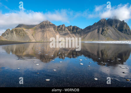 Paesaggio islandese, riflesso della montagna Vestrahorn nelle acque dell'Oceano Atlantico. Penisola Stokksnes, Hofn, Islanda Foto Stock