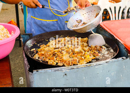 Il venditore è la frittura e la cottura di mitilo può essere visto da cucina di strada in Thailandia Foto Stock