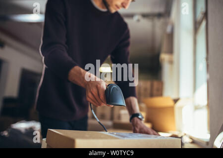 On-line venditore lavora in ufficio. Uomo al lavoro su ordini on line, la scansione del pacco prima della spedizione al cliente. Foto Stock