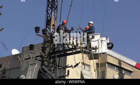 Gli elettricisti del popolo israeliano Electric Co il fissaggio ad alta tensione delle linee elettriche, la sostituzione di un trasformatore dopo il grande incendio di Haifa, Israele, Dicembre 25, 2018 Foto Stock