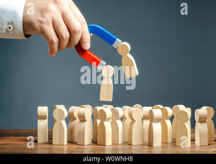 Imprenditore con un magnete tirando figure in legno di persone dalla folla. Il reclutamento di nuovi lavoratori, headhunters. La formazione di un nuovo team di business di ap Foto Stock
