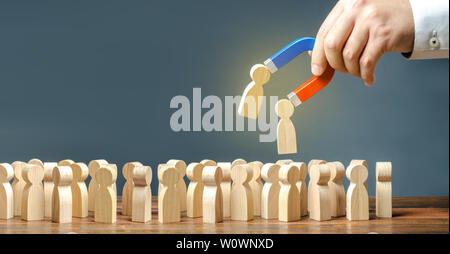 Imprenditore con un magnete tira figure in legno di persone al di fuori della grande folla. Il reclutamento di lavoratori. Ricerca di richieste di persone e lavoratori con la necessa Foto Stock