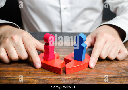 Uno psicologo collega le due metà di un cuore spezzato con le figure di un uomo e di una donna in piedi su di essi. Assistenza psicologica in reconciliatio Foto Stock