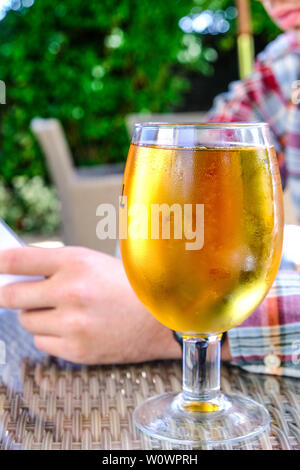 Vetro a freddo Sidro di mela su un tavolo con un Uomo la lettura di un menu di cibo Foto Stock