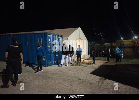 Malaga, Spagna. Il 28 giugno, 2019. I migranti lasciare una tenda della Croce Rossa spagnola come si cammina verso una polizia van dopo il loro arrivo al porto di Malaga.Spagna's Maritime Rescue service salvato 50 migranti a bordo di un battello che attraversa il Alboran Mare e li ha portati al porto di Malaga, dove sono stati assistiti dalla Croce Rossa spagnola. Credito: SOPA Immagini limitata/Alamy Live News Foto Stock