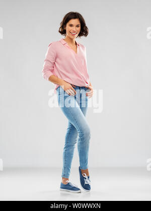 Giovane donna in camicia a righe, jeans e scarpe da ginnastica Foto Stock