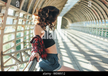 Ritratto di giovane attraente brunette donna street dancer ginnasta sul ponte stradale al sunrise Foto Stock