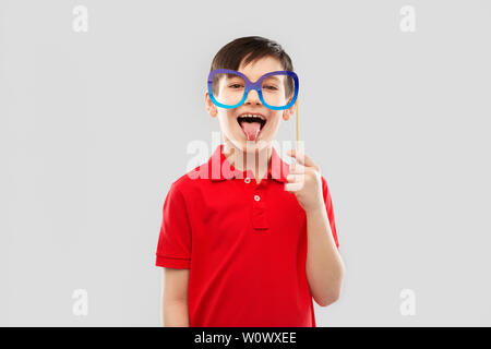 Felice ragazzo con grandi bicchieri di carta che mostra la linguetta Foto Stock