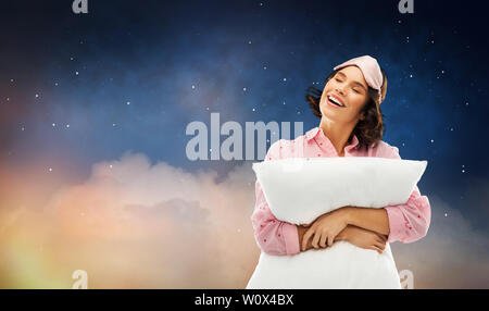 Donna con cuscino in pigiama e occhio maschera del sonno Foto Stock