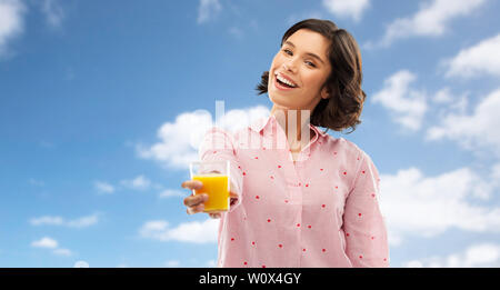 Felice giovane donna in pigiama holding succo di arancia Foto Stock