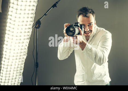 Bel giovane in possesso di una fotocamera reflex digitale. Foto Stock